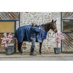 Cavalier mettant la couverture 50 g Classic 1200 D Equithème sur la sous couverture