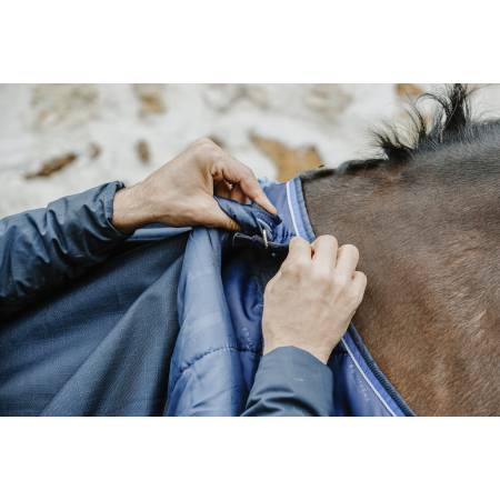 Zoom sur un cavalier accrochant la couverture 100 g Classic 1200 D Equithème à la sous couverture