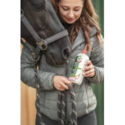 Cavalier tenant un flacon de lotion de soins Arbre à Thé Leovet devant la tête d'un cheval